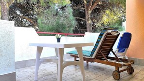 Un patio con una mesa blanca y una silla de madera con cojín azul.