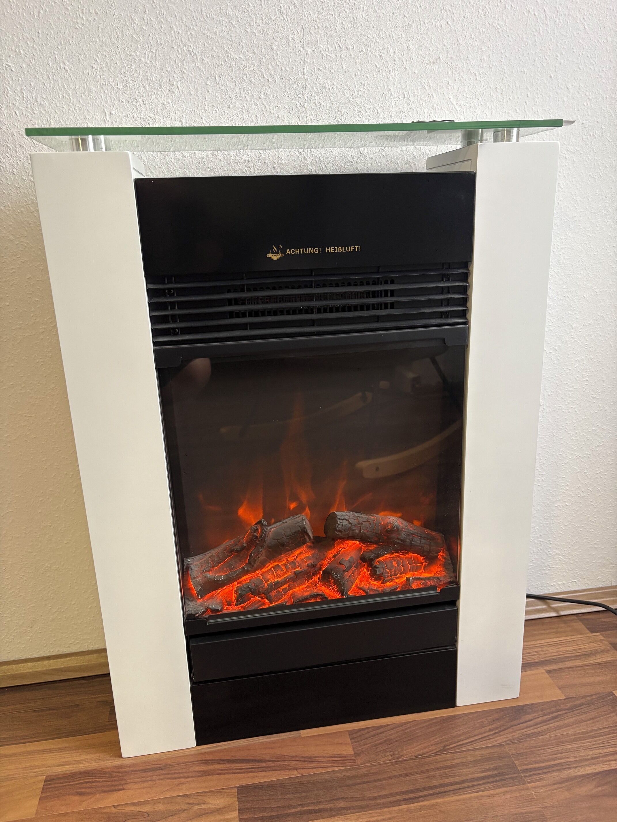 Moderni takka, jossa on lasinen yläosa ja näkyvät, palavat puut.