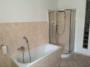 A bathroom with a bathtub, a shower, and a glass-enclosed shower stall. - Vacation apartment Reitzenhain (Marienberg)