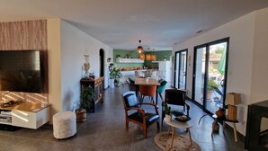 A modern living room with a TV, seating, and a dining area.