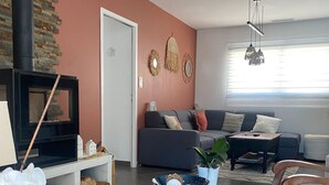 A living room with a fireplace, sofa, and wooden chairs.