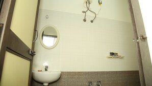 A bathroom with a sink, mirror, towel rack, and shower controls. - Arunachala Cottage (Tiruvannamalai)