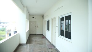 A corridor with a tiled floor, white walls, and doors with windows. - Arunachala Cottage (Tiruvannamalai)
