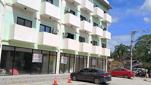 Een meerhoog gebouw met balkons, airconditioners en reclameborden voor commerciële ruimtes.