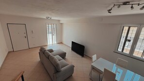 Un'ampia zona giorno con divano, TV a schermo piatto, tavolo da pranzo e finestra con vista.