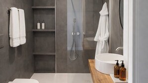 Un bagno moderno con un water sospeso, un lavabo ampio, una doccia e un mobile contenitore in legno.