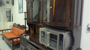 Un salon avec un meuble en bois foncé, un four à micro-ondes et un canapé.