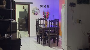 Un salon comprenant un coin repas, un téléviseur et un vase avec des fleurs.