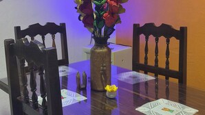 Une table à manger ornée d’un vase de fleurs, deux chaises et un élément décoratif mural.