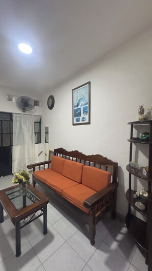A living room with a wooden sofa, a glass coffee table, a wall clock, a framed picture, and a shelf with decorative items. - Traditional homey house in romantic area (Puerto Vallarta)