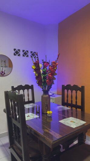 A dining table with a vase of flowers, two chairs, and a decorative mirror on the wall. - Traditional homey house in romantic area (Puerto Vallarta)