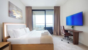 A modern hotel room with a large bed, a desk with a chair, a flat-screen TV, and a balcony with curtains. - Studio in Trillionaire - Private Jacuzzi (Dubai)