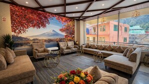 A hotel room with a large window, a sofa, armchairs, a coffee table, and a mural of a mountain. - Mount Hayat Hotel  (Naran)