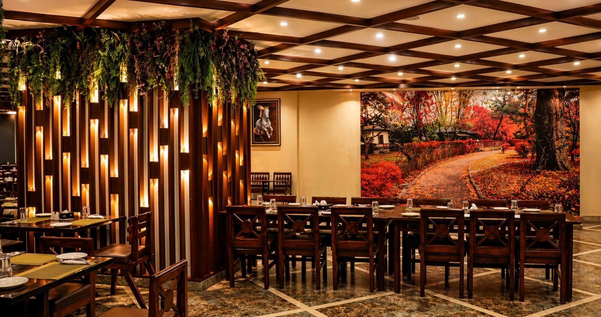 A restaurant with a long table, chairs, and a mural of a red autumn landscape.