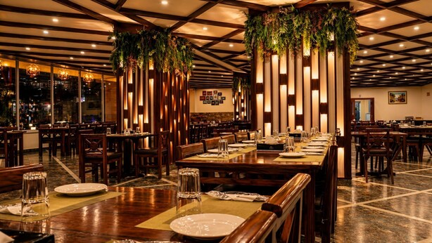 A restaurant with wooden tables, chairs, and hanging greenery. - Mount Hayat Hotel  (Naran)