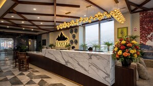 A reception desk with a marble top, a clock, and a wall-mounted sign that reads 'HAYAT'. - Mount Hayat Hotel  (Naran)
