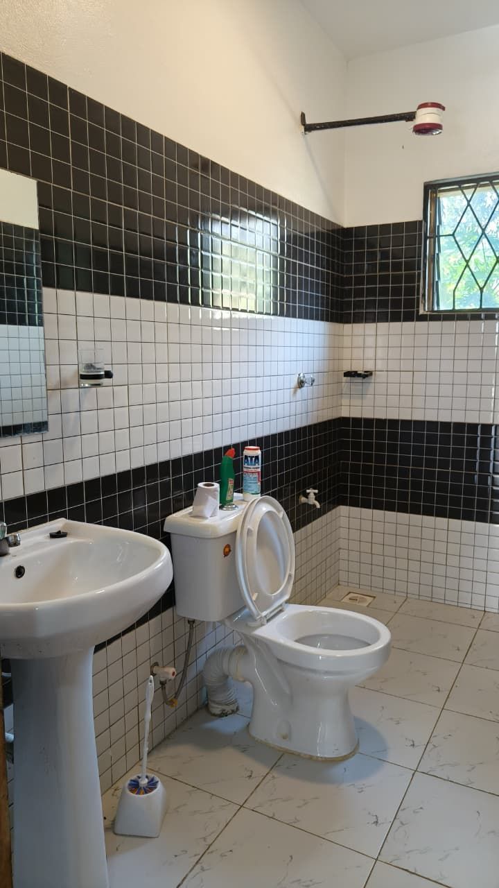 A bathroom with a toilet, sink, and tiled walls.