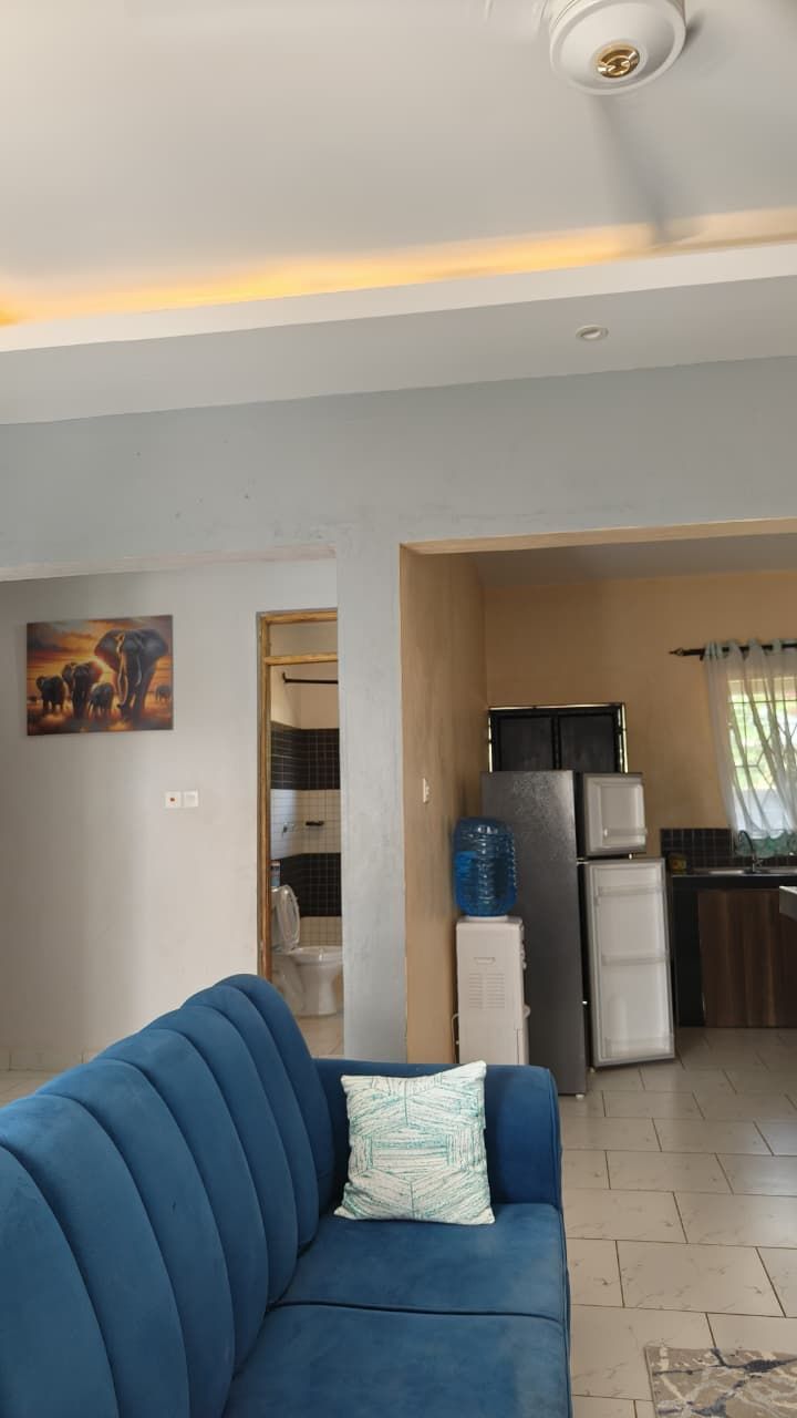 A living room with a blue sofa and a painting on the wall.