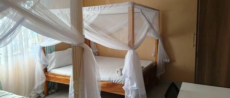 A single bed with a canopy, a wooden headboard, and a white mattress.