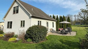 Una casa de un piso con techo inclinado y un patio con mobiliario exterior.