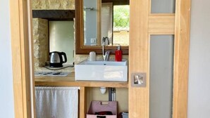 A compact bathroom with a white sink, a mirror, a towel, and a pink storage box. - Maison Chaumont: Quiet Retreat with Chateau Views (Vézac)