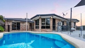Una piscina con una casa al fondo.