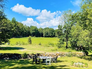A grassy outdoor area with a stone wall, a table, and chairs. - 6 Person Holiday Home in Backaryd (Backaryd)
