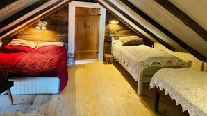 A cozy attic bedroom with two beds, wooden beams, a sloped ceiling, and a small wooden door. - 6 Person Holiday Home in Backaryd (Backaryd)