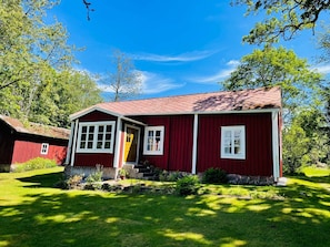 A red wooden house with a porch, a front door, and a small front yard. - 6 Person Holiday Home in Backaryd (Backaryd)