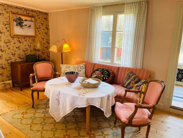 A cozy room with a round table, two chairs, a sofa, and a window with curtains. - 6 Person Holiday Home in Backaryd (Backaryd)