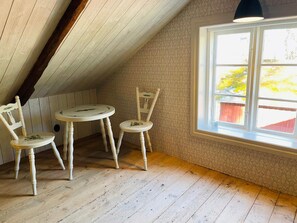 A room with a sloped ceiling, a small round table, two chairs, and a window with a view of greenery outside. - 6 Person Holiday Home in Backaryd (Backaryd)