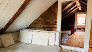 A cozy attic bedroom with a white sofa, wooden beams, and a wooden floor. - 6 Person Holiday Home in Backaryd (Backaryd)
