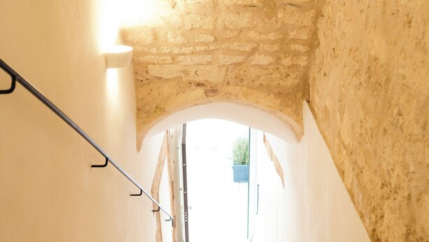 A staircase with a stone ceiling and white walls, leading to a bright outdoor area. - Saludu Boutique (Porto Torres)