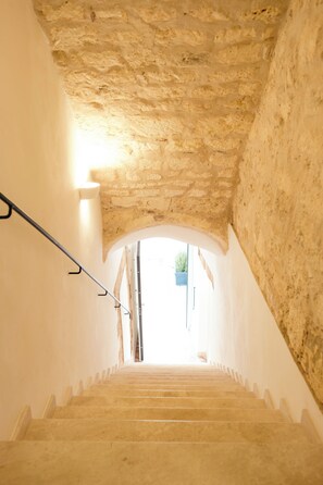 A staircase with a stone ceiling and white walls, leading to a bright outdoor area. - Saludu Boutique (Porto Torres)