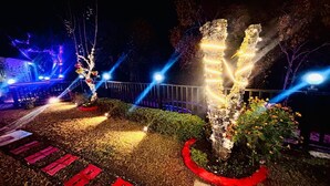 A well-lit garden area with trees and a pathway. - B'NEST By Baan Home Stay (Siloti Pant)