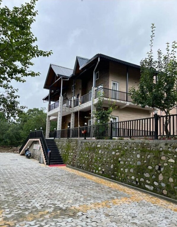 Un immeuble à plusieurs étages, doté d’une façade en pierre, de balcons et d’un escalier menant à l’entrée.