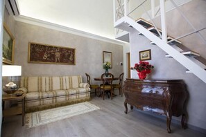 Een woonkamer met een bank, een houten dressoir, een eettafel met stoelen en een trap.