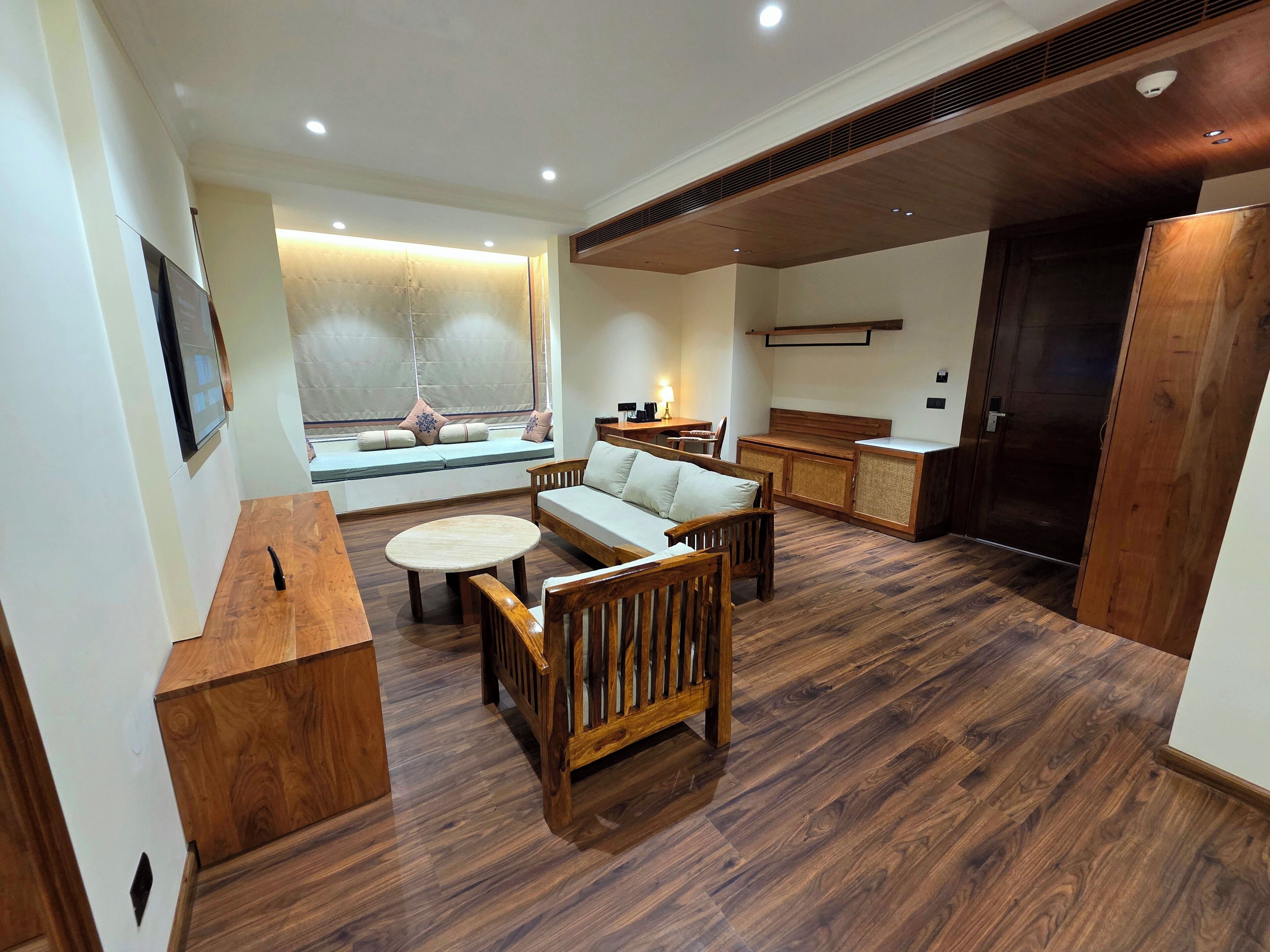 A modern living room with a sofa, chairs, a coffee table, a wooden cabinet, and a built-in bench with cushions.
