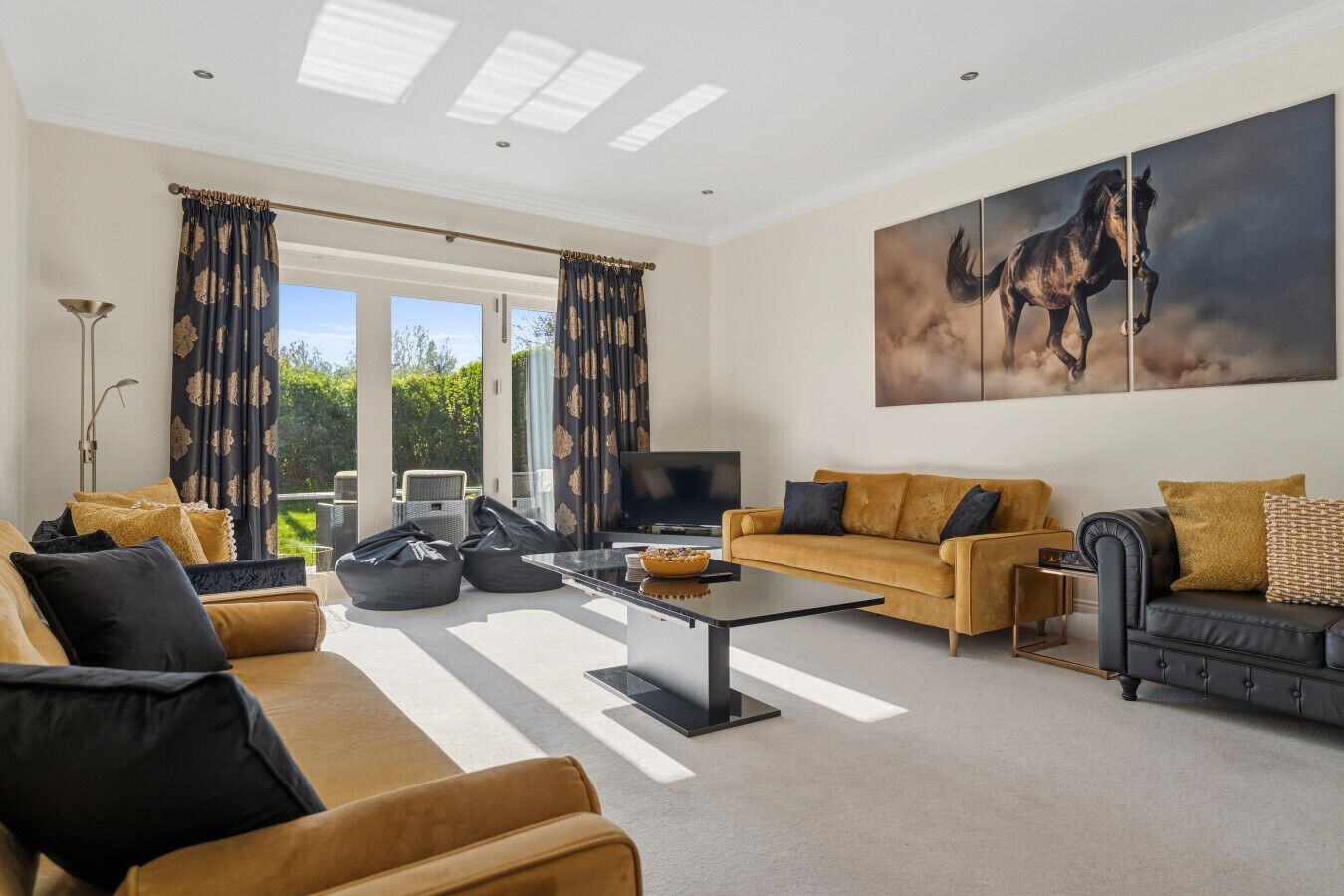 A spacious living room with a sofa, coffee table, and a large painting of a horse.