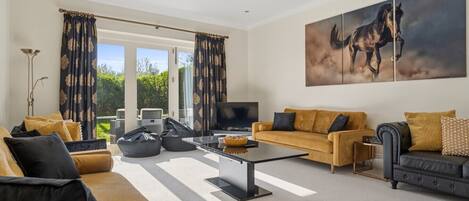 A spacious living room with a sofa, coffee table, and a large painting of a horse.