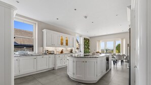 Una cocina moderna con armarios blancos, una isla central y vistas al exterior.