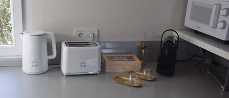 A kitchen with a toaster, kettle, microwave, and a small wooden box on the counter.