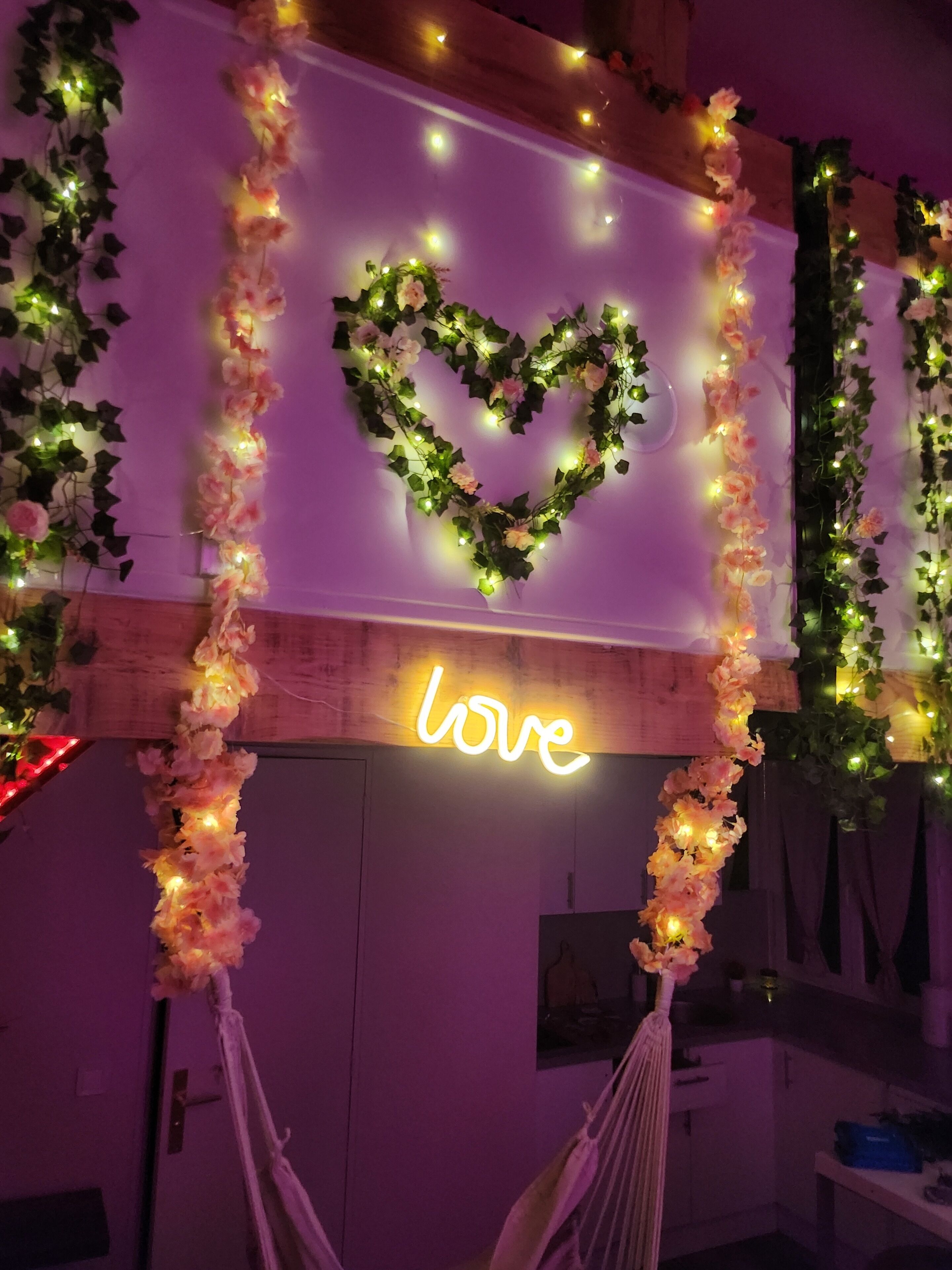 Una stanza illuminata da un neon con la scritta 'love' e una decorazione a forma di cuore luminoso.