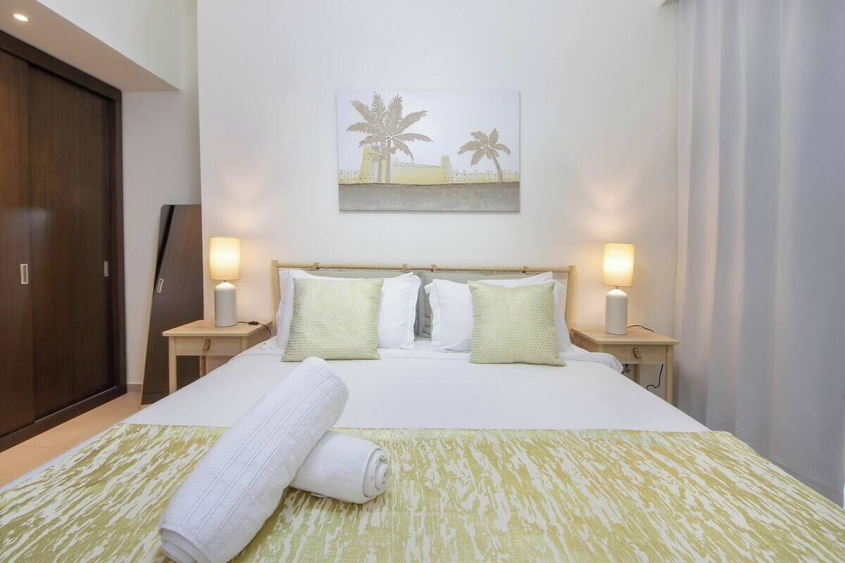 A hotel room with a bed, two bedside tables, a headboard, and a wall-mounted picture.