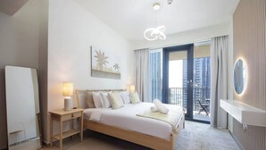 Een moderne hotelkamer met een groot bed, bedlampen, een kleine tafel, een spiegel en uitzicht op de stad vanuit een balkon.