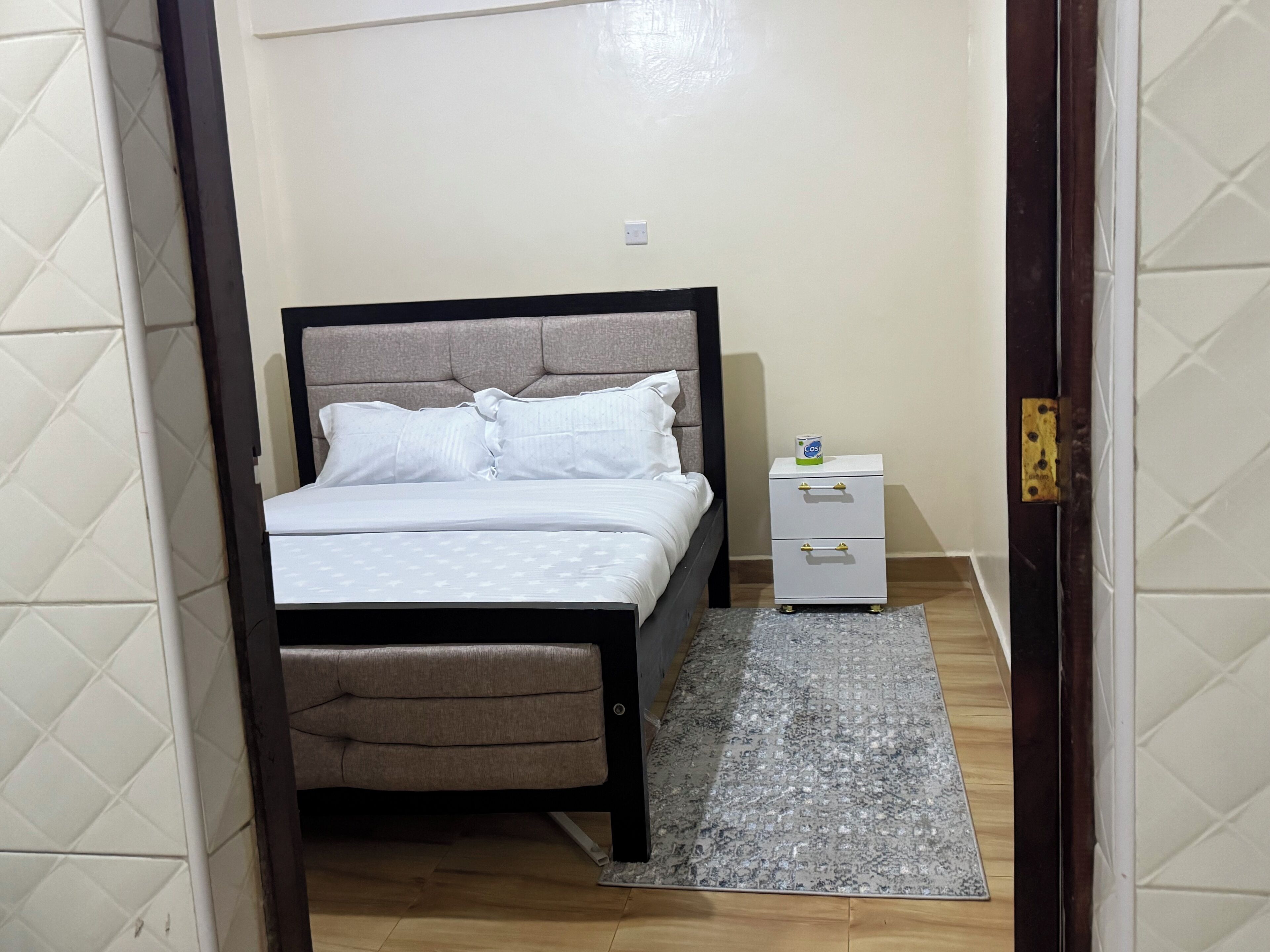 A bedroom with a bed, bedside table, and a rug.