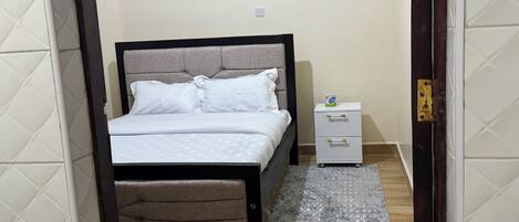 A bedroom with a bed, bedside table, and a rug.