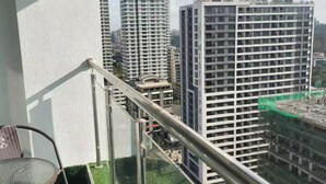 A balcony with a metal railing, a small table, and chairs. In the background, there are high-rise buildings and a construction site. - New 2 Besrooms in Westlands Near GTC on 20th topfloor with a spectacular view (Nairobi)