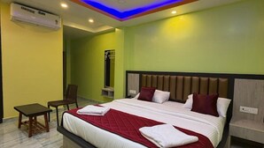 A modern hotel room with a large bed, a desk, a chair, and an air conditioning unit. - Sri Krish Resort  (Port Blair)