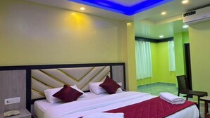 A modern hotel room with a large bed, a nightstand, and a seating area. - Sri Krish Resort  (Port Blair)